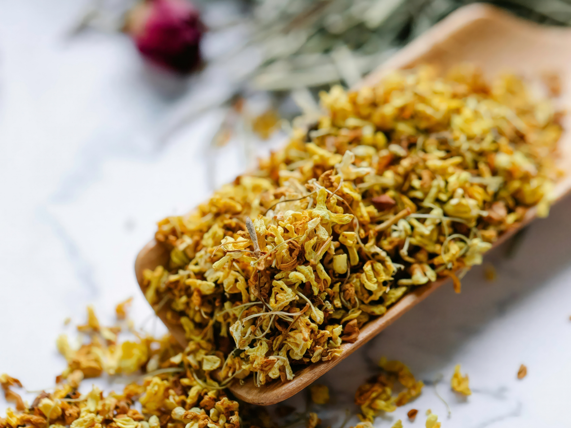 Close-up of a wooden spoon filled with dried yellow flower petals or herbs