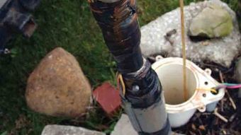 Broken white mug beside a weathered pole among rocks and grass outdoors
