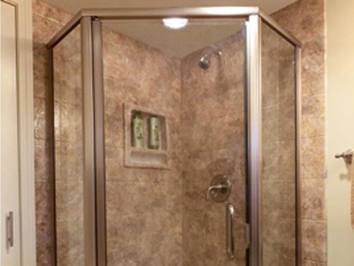 a bathroom with a walk in shower with a glass door .
