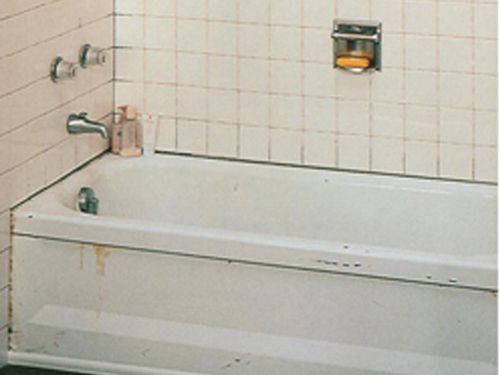 a bathtub in a bathroom with a soap dispenser on the wall