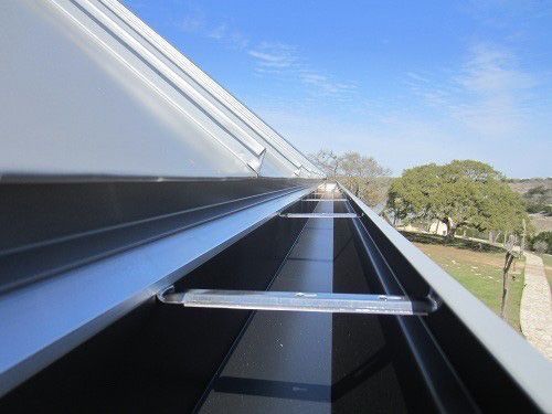 a close up of a gutter on a roof with trees in the background