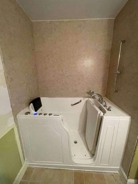 A walk in tub with a door in a bathroom.