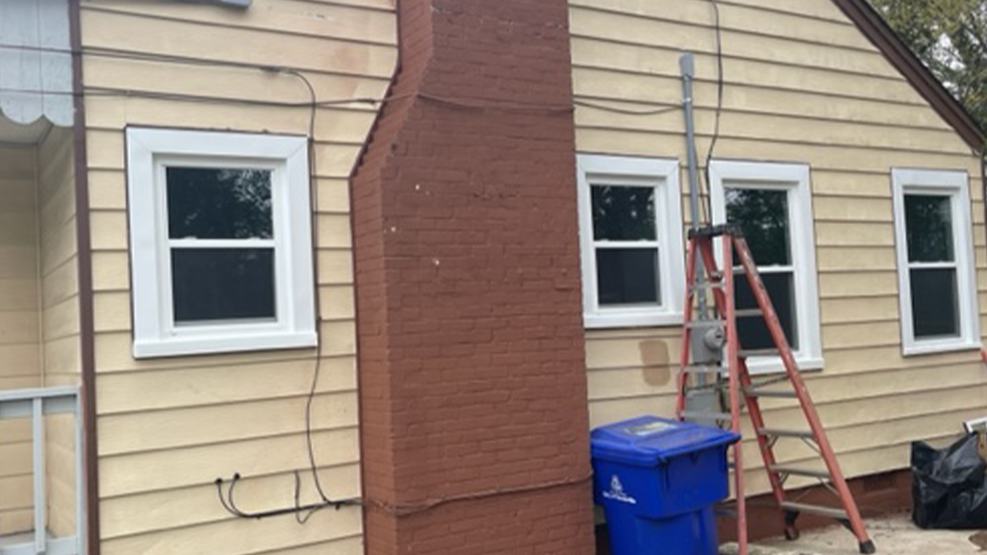 A house with a blue trash can in front of it and new windows