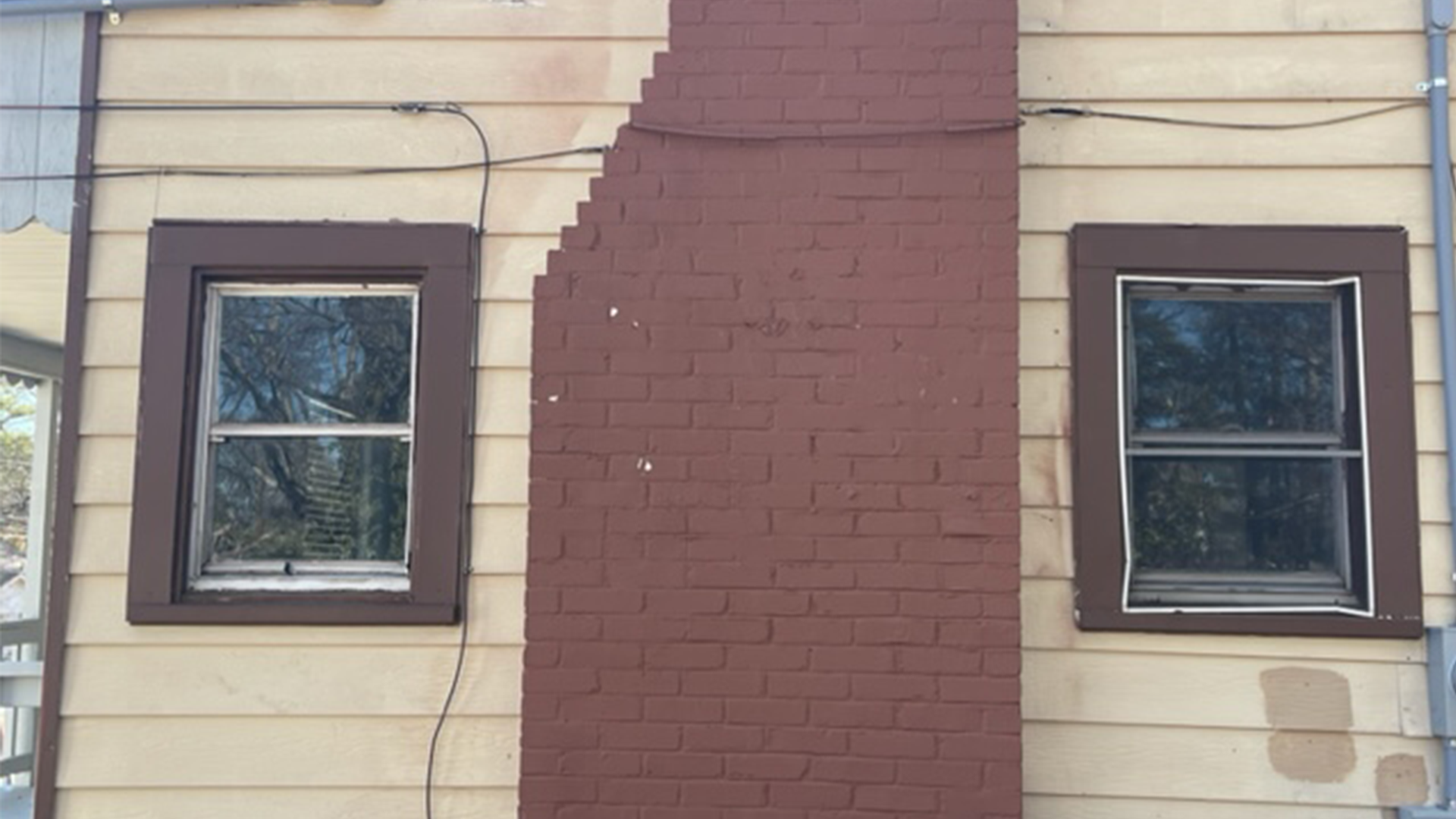 A house with a chimney on the side of it and two old windows.