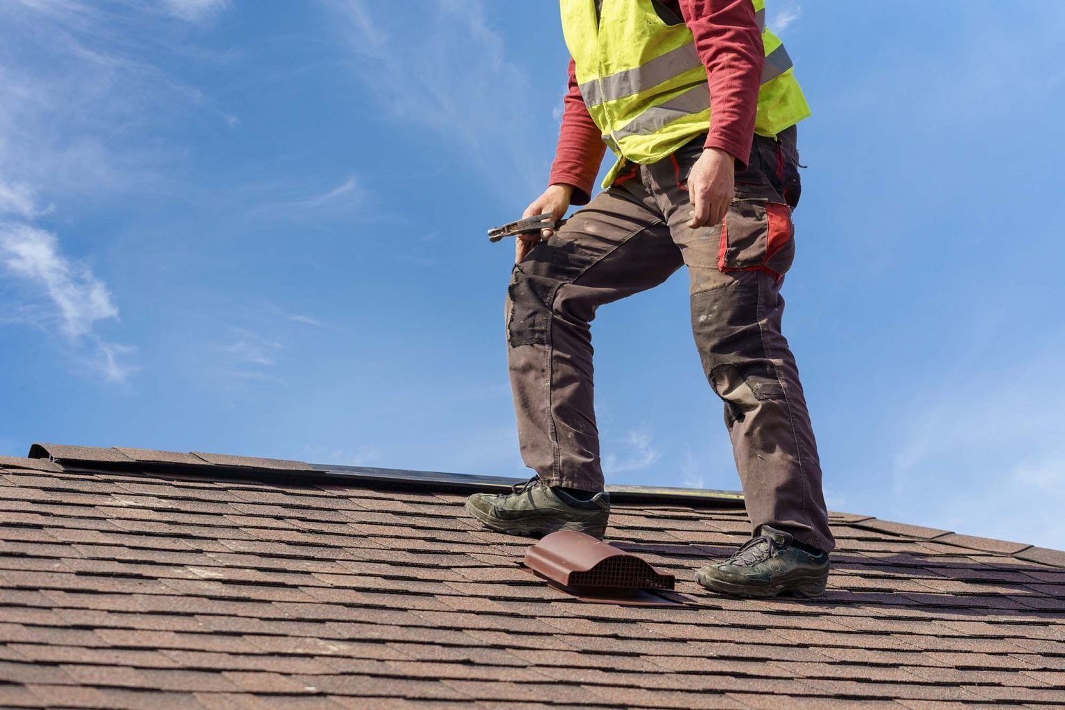 a man is standing on top of a roof holding a hammer .