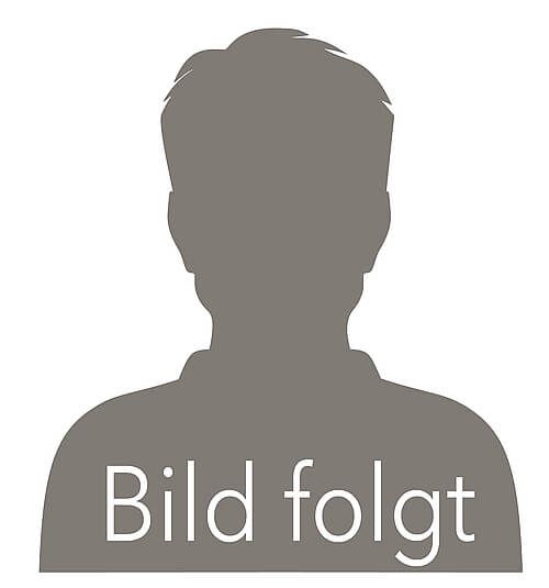 Eine Frau im blauen Kittel lächelt vor einem Mikroskop