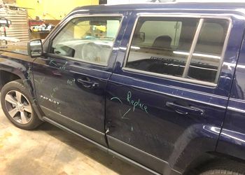 a blue jeep patriot is parked in a garage .