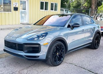 a blue porsche cayenne turbo is parked in front of a building .