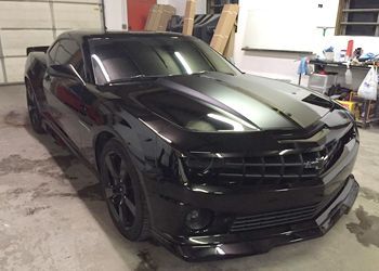 a black car is parked in a garage next to a garage door .