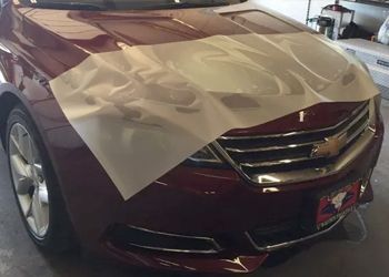 a red car with a piece of paper on the hood .