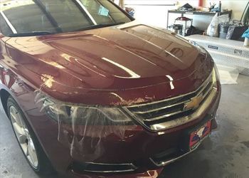 a red car is wrapped in plastic and sitting in a garage .