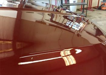 a close up of a red car hood in a garage .