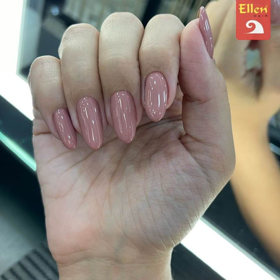 Uma mão com unhas ovais esmaltadas, de um tom rosa-claro. A mão está relaxada, com os dedos ligeiramente curvados.
