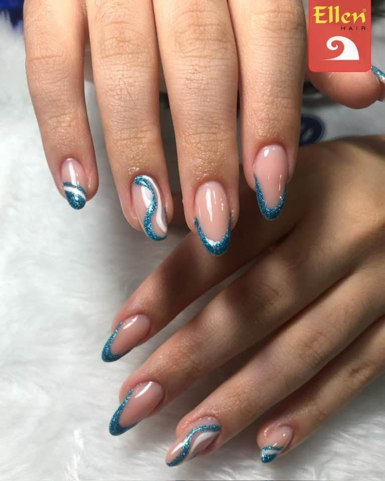Mãos com unhas amendoadas com base transparente e contorno brilhante azul-petróleo e detalhes ondulados.