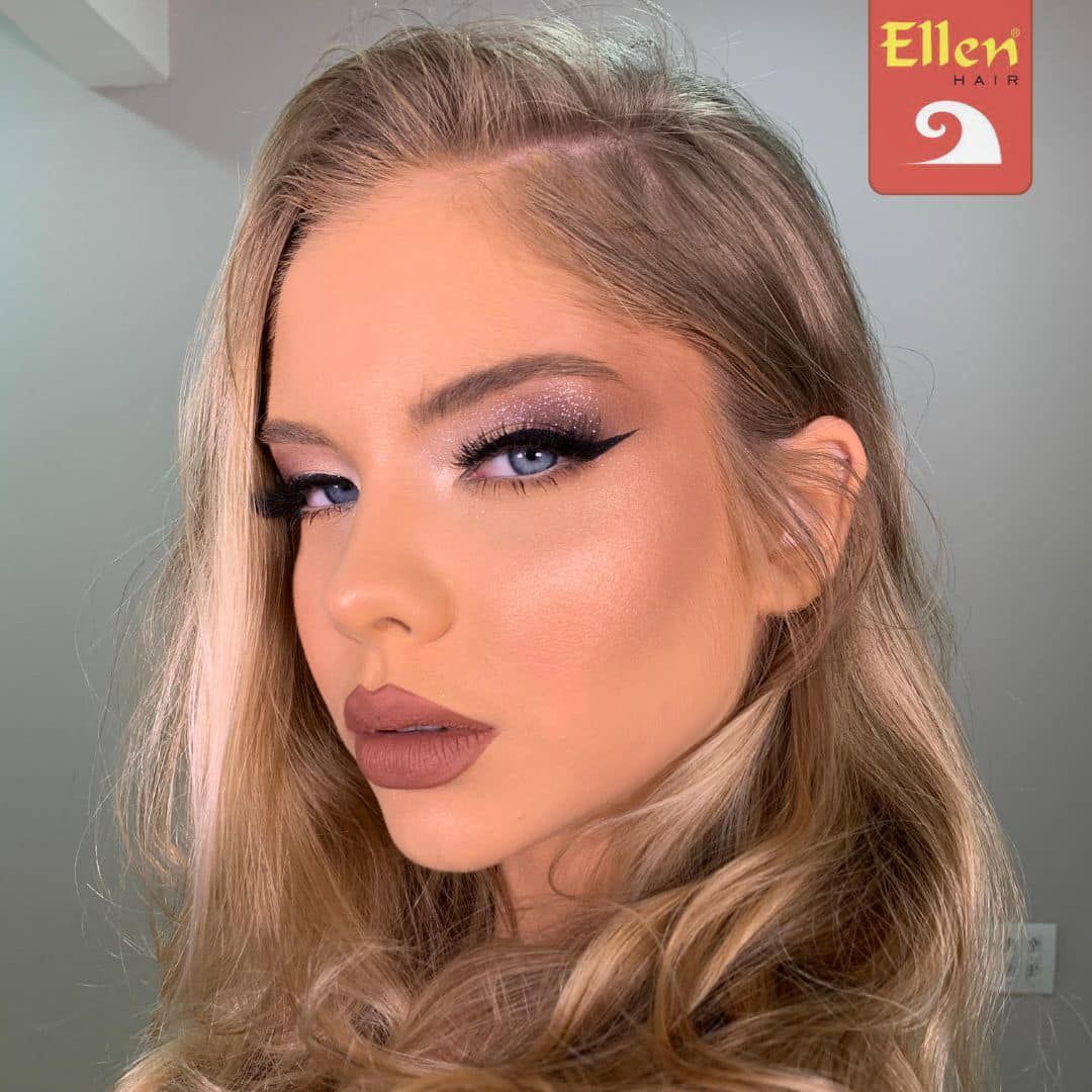 Mulher loira com maquiagem glamourosa, incluindo olhos esfumaçados e batom nude, olhando para a câmera.