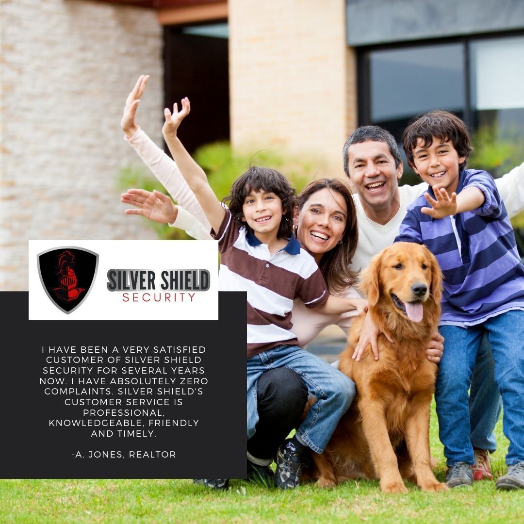 Family with dog outside Silver Shield Security sign, smiling and waving in front of a house.