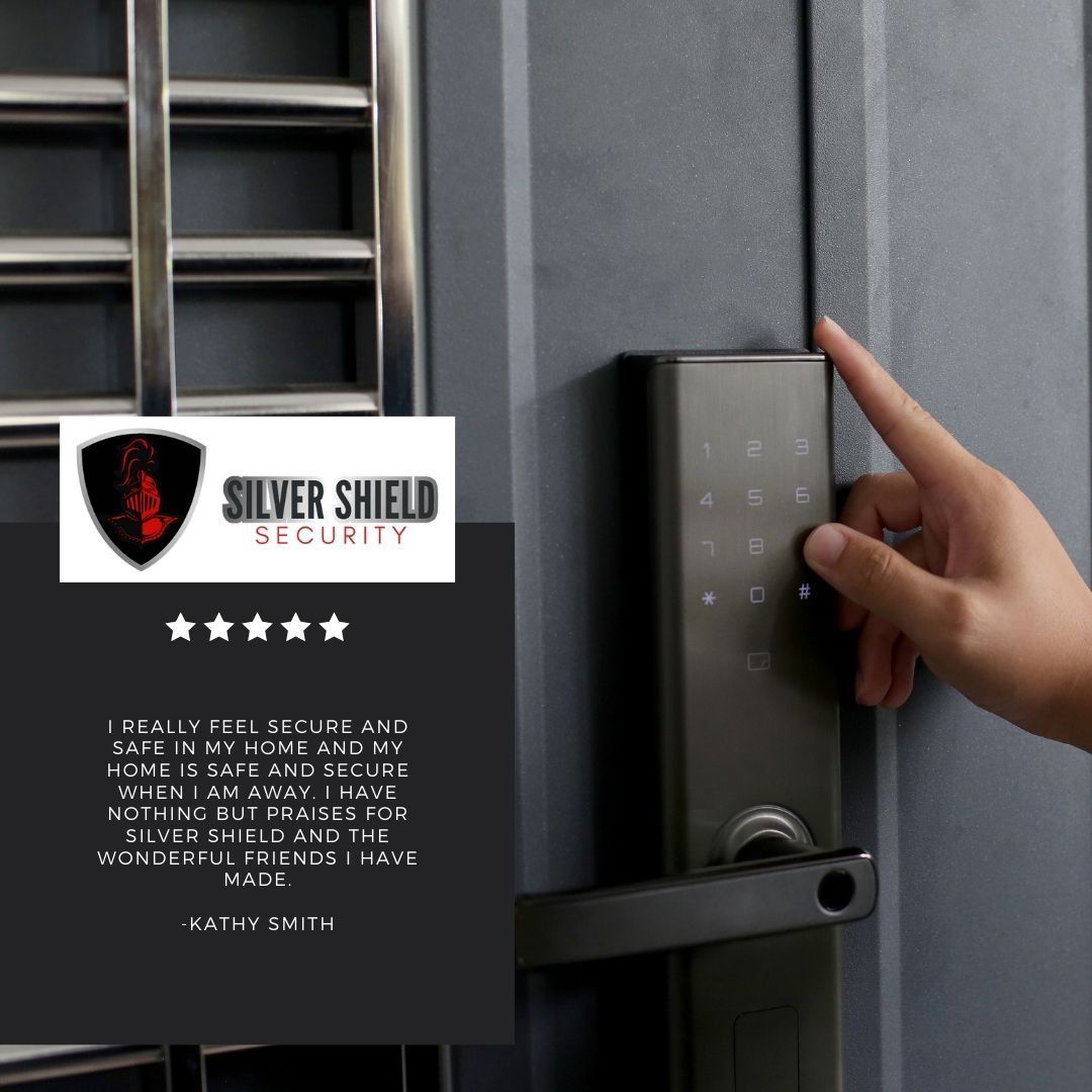 Hand entering a code on a silver digital door lock beside a grey security door with a shield logo.