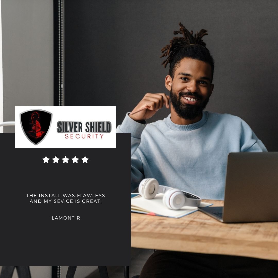 Smiling man at a desk with laptop and headphones beside a Silver Shield Security logo and rating graphic
