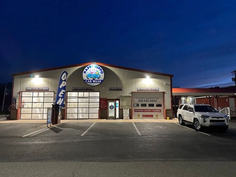 Night view of a lit garage-style building with a white truck parked outside under a dark blue sky