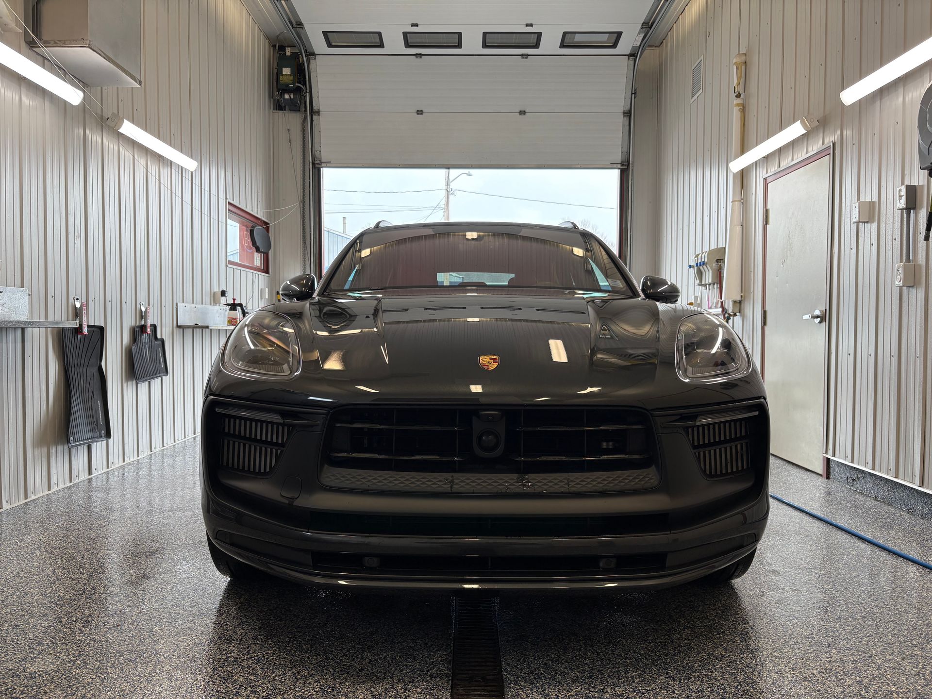 Black SUV parked inside a bright car wash bay, viewed from the front