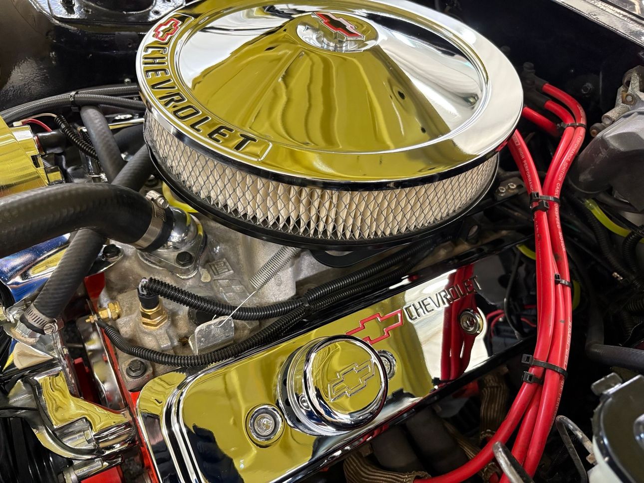 Chrome V8 engine with gold air cleaner and red ignition wires in a car engine bay