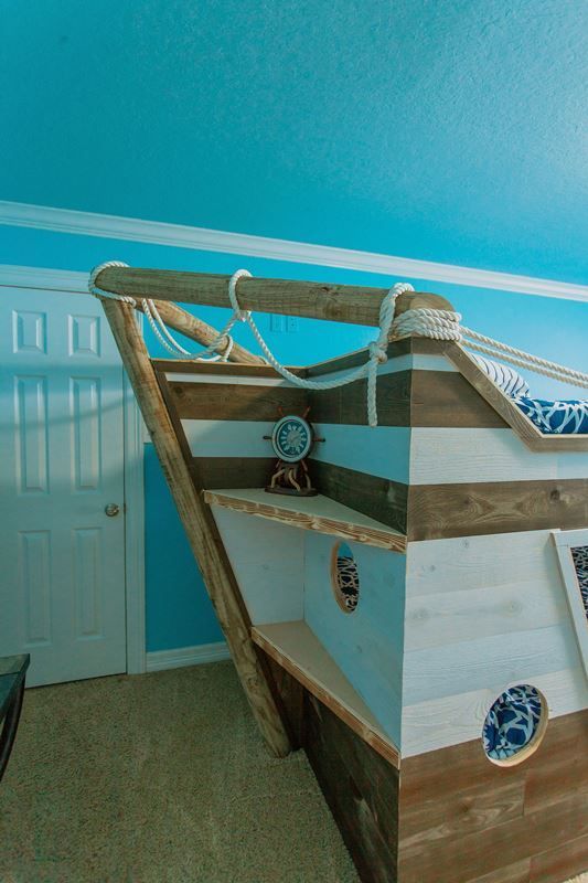 A bunk bed in the shape of a pirate ship in a bedroom.