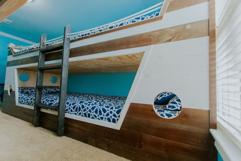 A bunk bed in a room with blue walls and a window.