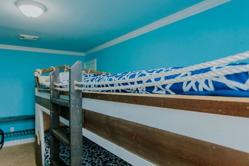 A bunk bed with a ladder in a room with blue walls.