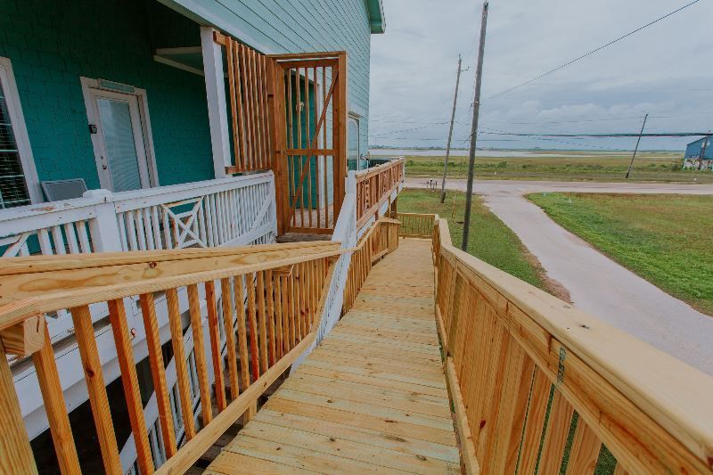 A wooden ramp leading up to a house with a view of the ocean.