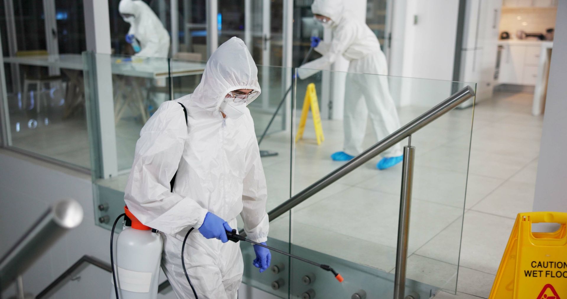 Pest control technicians in PPE treating a commercial building interior