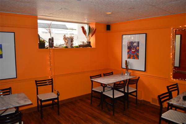 A restaurant with orange walls and tables and chairs