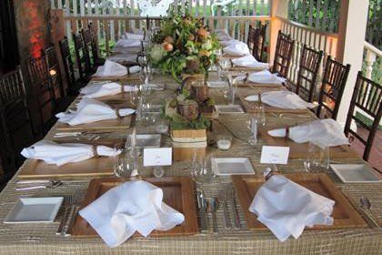 A long table with plates , utensils , and flowers on it