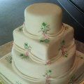 A white wedding cake with pink flowers on it is sitting on a table.