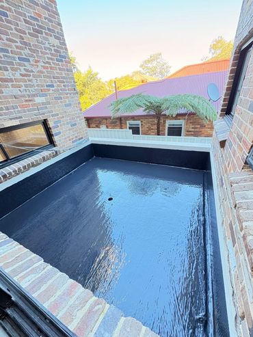 Black waterproof-coated pool or tank interior with light concrete edges