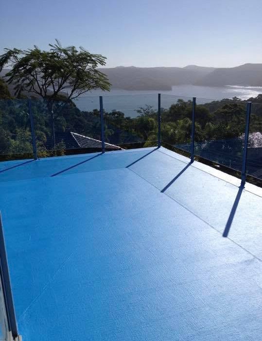 Blue rooftop terrace overlooking a bay and green hills under a hazy sky. Blue rooftop terrace overlooking a bay and green hills under a hazy sky.