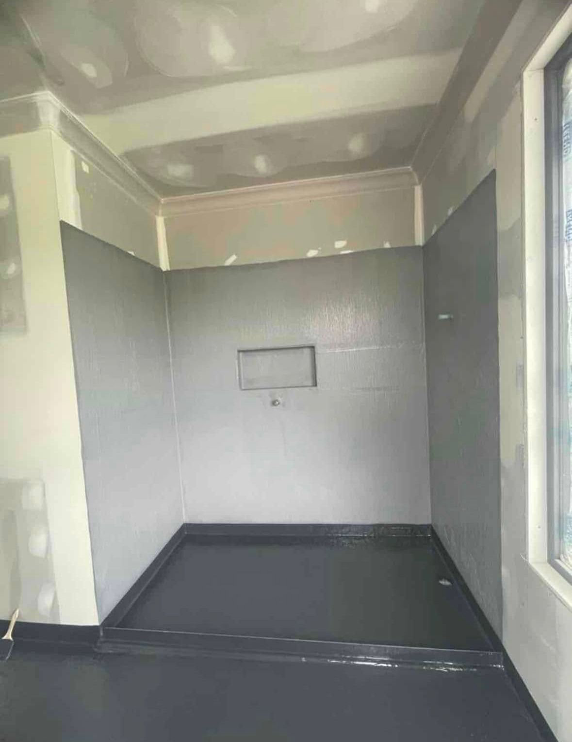 Empty gray interior room with dark floor and a small wall-mounted fixture.