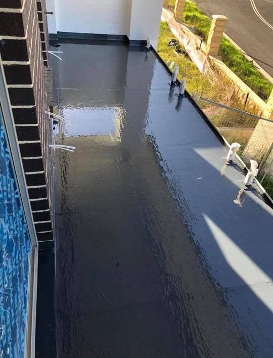 Rainy rooftop walkway with standing water beside a building and road