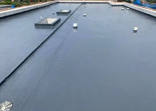 Flat gray rooftop with vents and utility boxes under overcast light