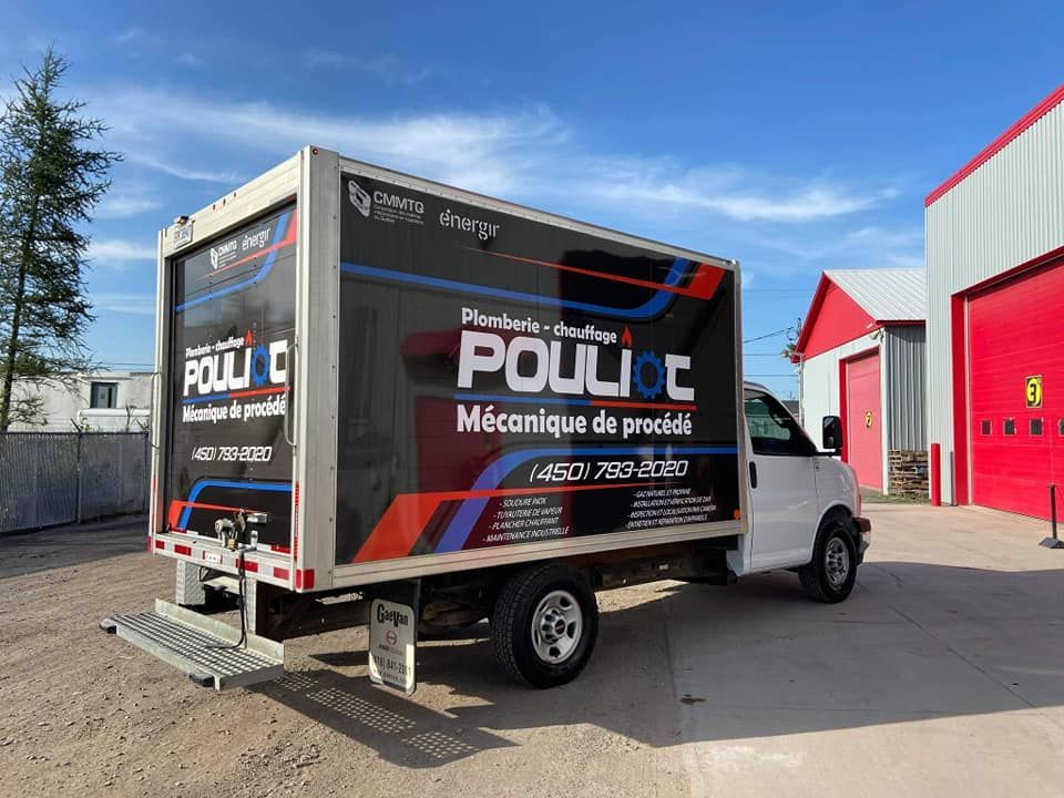 Un camion blanc est garé devant un bâtiment rouge.
