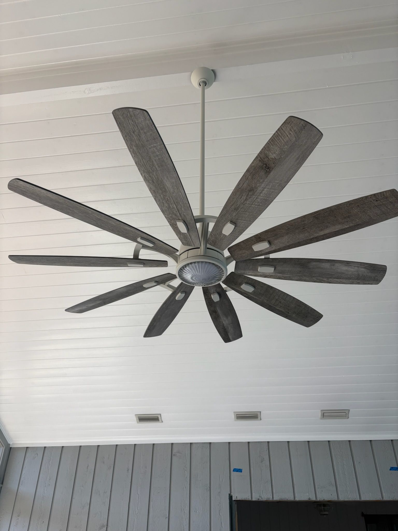 Ceiling fan with ten gray blades, mounted on white ceiling.