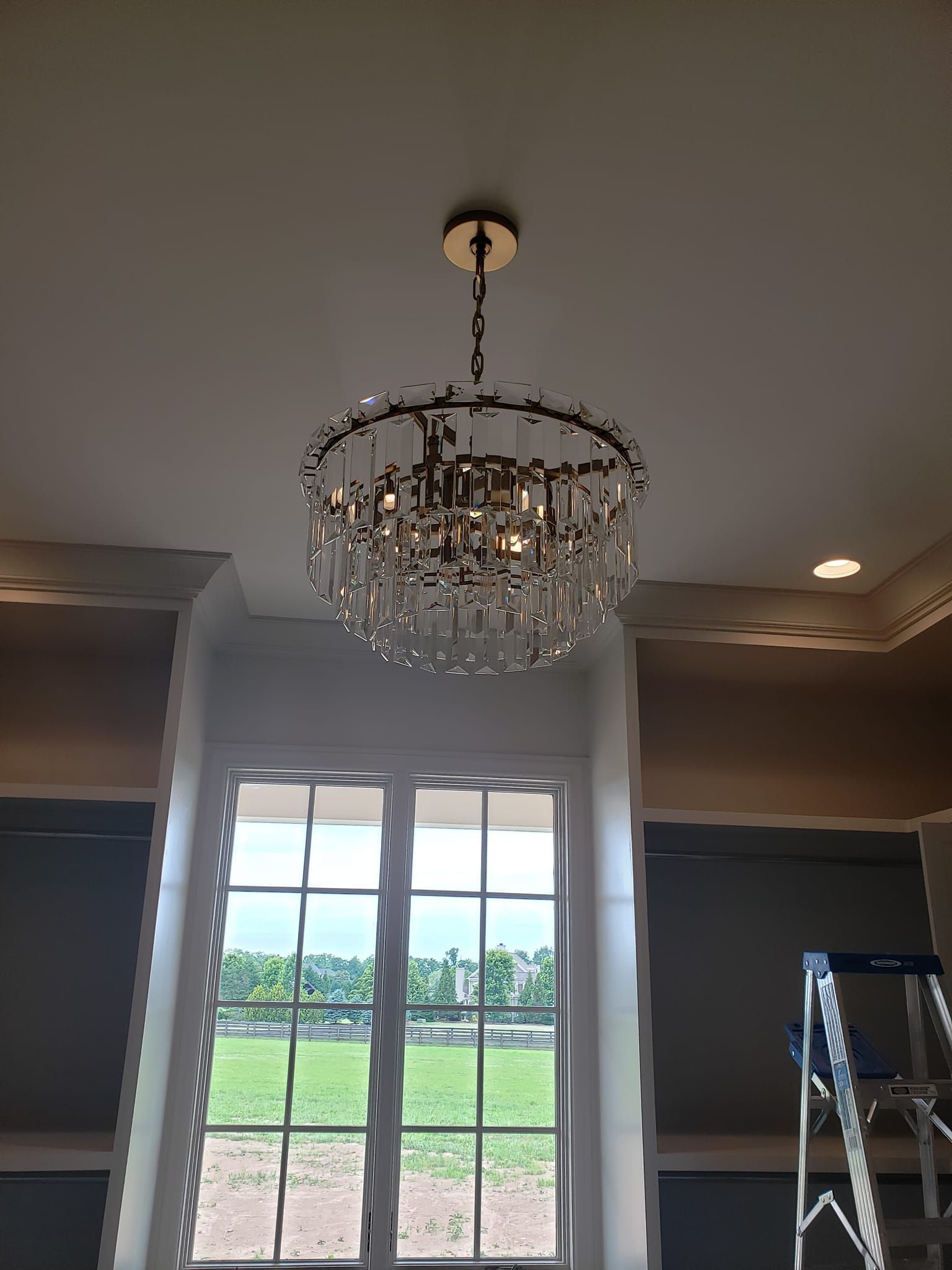 A chandelier is hanging from the ceiling in a room next to a window.