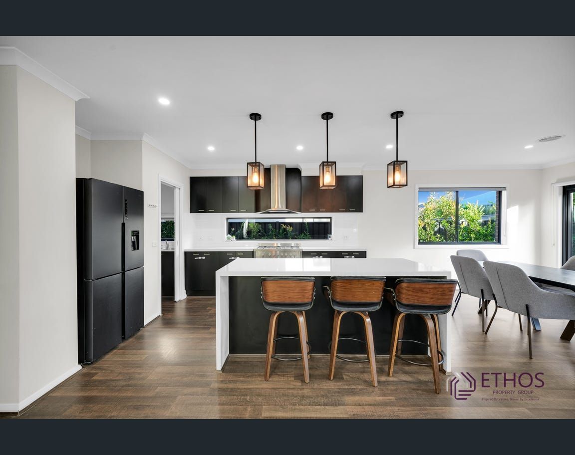Modern kitchen with dark cabinetry, white countertops, and a large island with bar stools.
