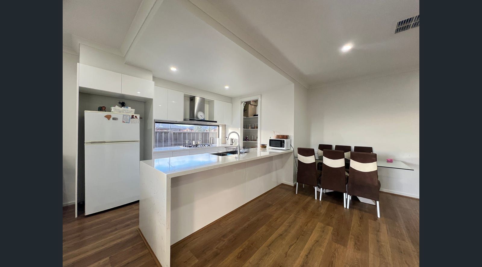 Bright, modern kitchen with white cabinets, island, stainless steel range hood
