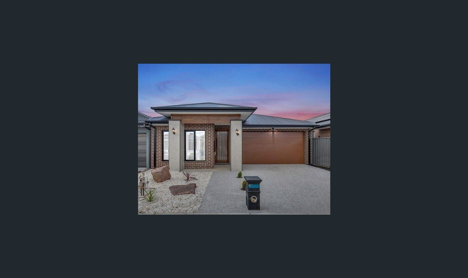 Modern home exterior with a garage and front yard with rocks.