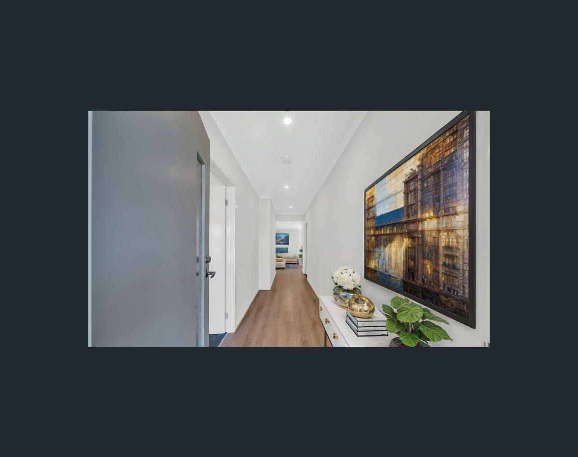 Hallway with light wood floors, white walls, and a decorative painting. A console table displays flowers and greenery.
