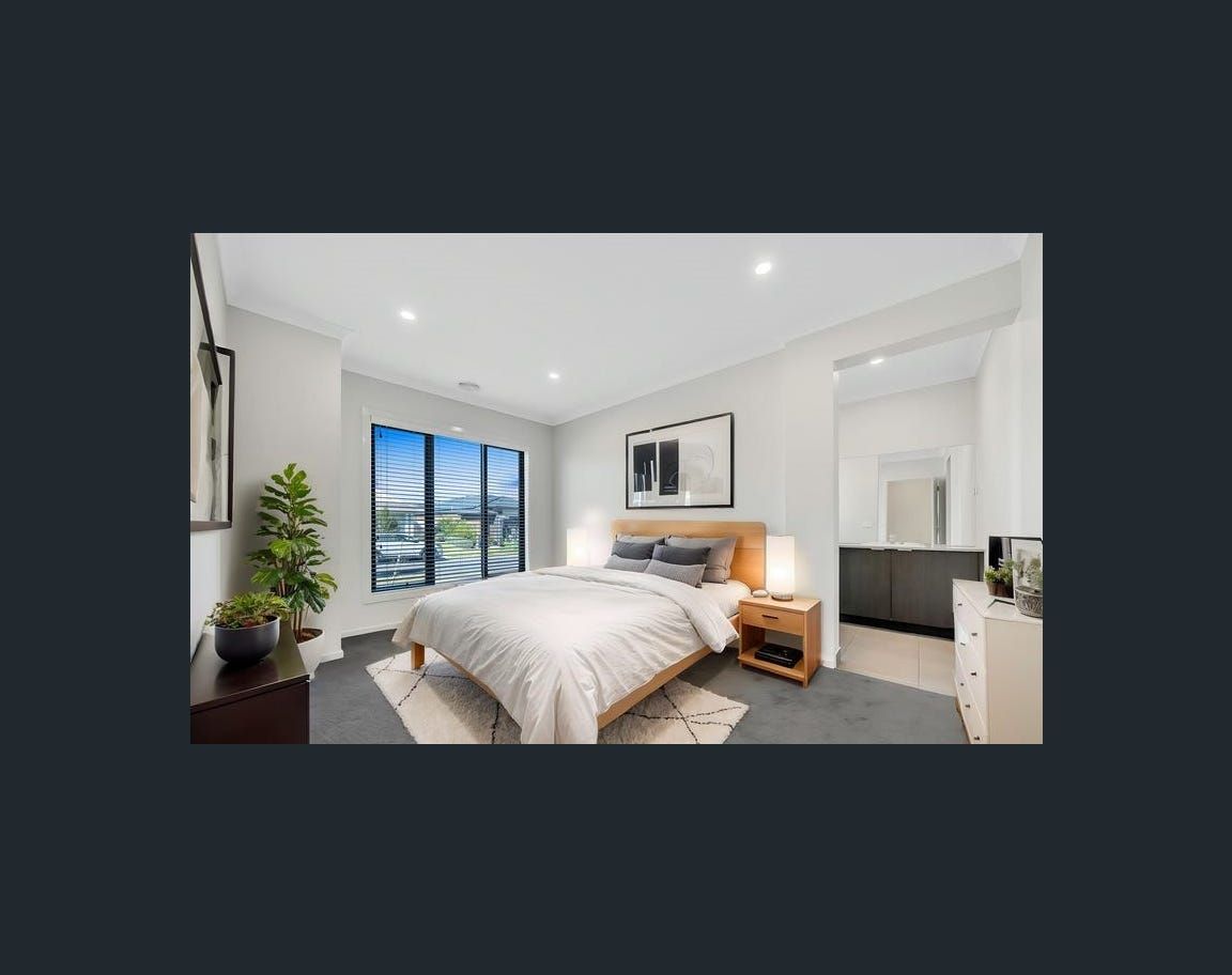 Bedroom with a bed, nightstands, and large windows overlooking a cityscape. It has neutral colors and modern decor.