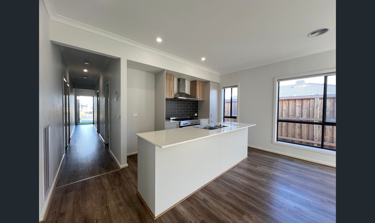 Modern kitchen with island, stainless steel appliances, and wood-look flooring.
