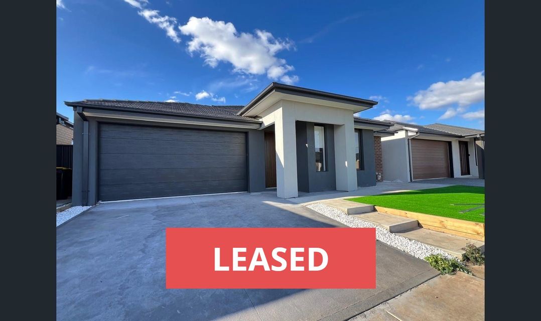 A modern house with gray garage doors and a "LEASED" banner in front of a blue sky.