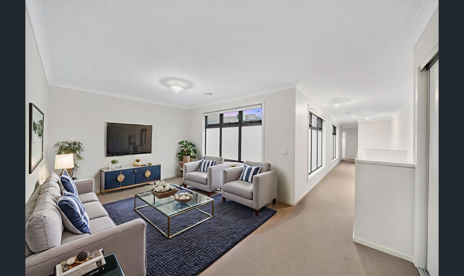 Modern living room with gray sofas, blue accents, and a dark rug.