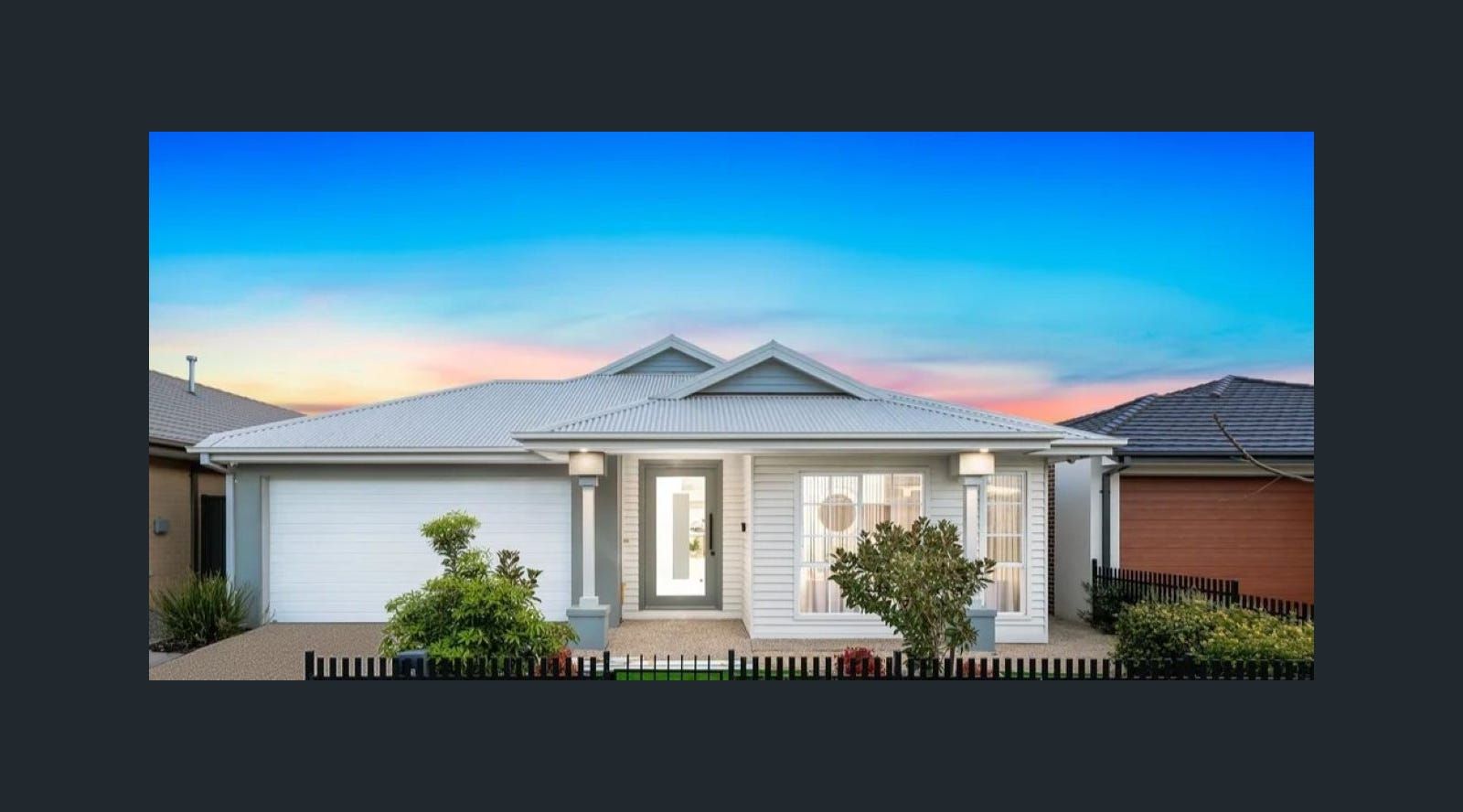 A light gray house with white trim, a blue sky, and landscaping.